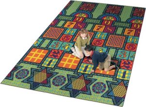 two kids playing on a large rug with hopscotch, checkers, tic-tac-toe, chinese checkers, and chess boards.
