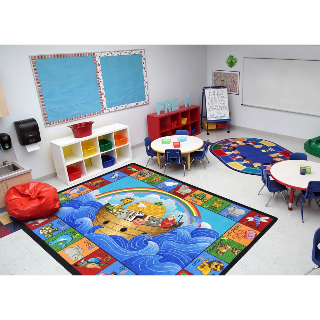 Colorful classroom with educational rug, tables, and chairs.